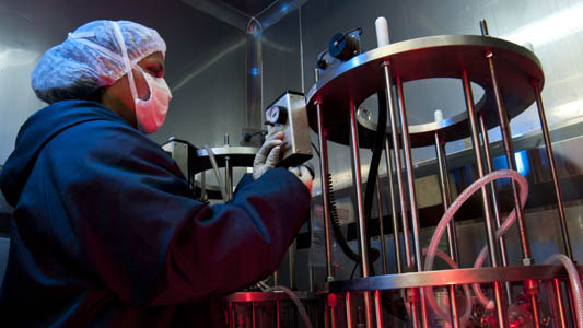 Foto de una profesional de laboratório ante una máquina